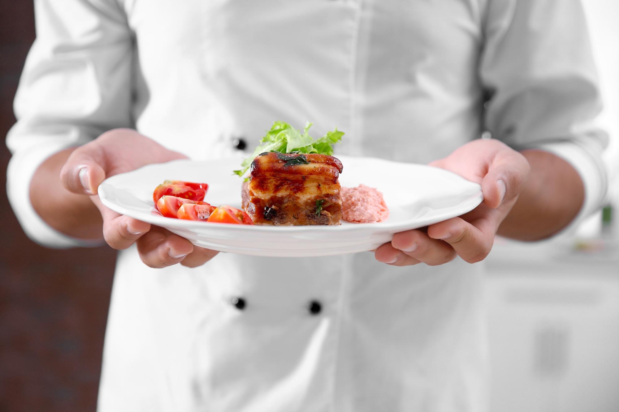Chef demonstrating technique with plated dish